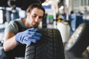 auto mechanic inspects car tire before repair