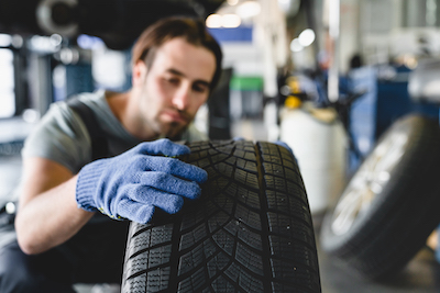 auto mechanic inspects car tire before repair