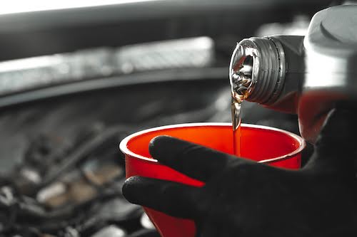 close-up of a Vancouver auto mechanic pouring motor oil